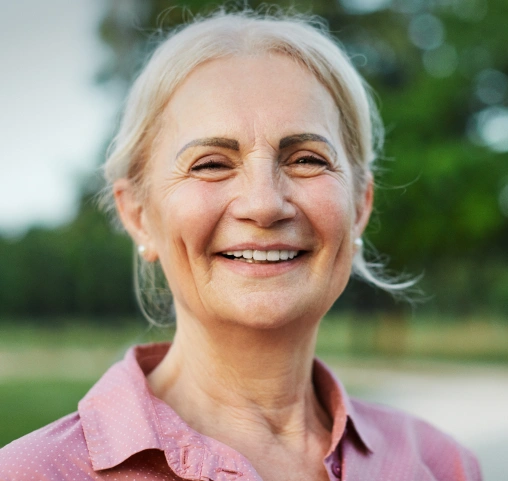 Smiling older woman with a complete, healthy smile after tooth replacement treatment.